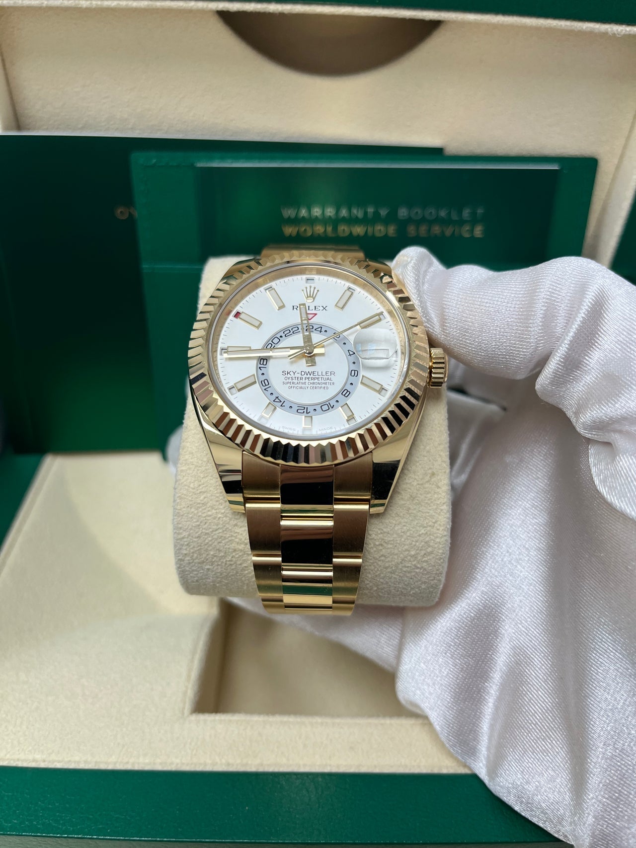 Close-up of Rolex Sky-Dweller white dial with off-center GMT ring, stick markers, and fluted yellow gold bezel – pre-owned 2025 model in unworn condition with box and papers – globalskydiamond.com